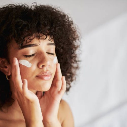 Cream, moisturizer and facial black woman in skincare, beauty or cosmetics promotion on white wall background. Face, calm and gen z people or model lotion, essential oil or moisturizer for skin care